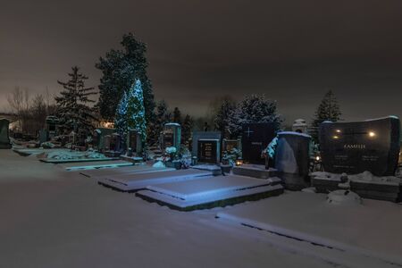 Bright graves in a winter night at the cemetery with snowの写真素材
