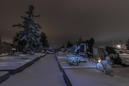 Light and snow layer on graves in a cemetery