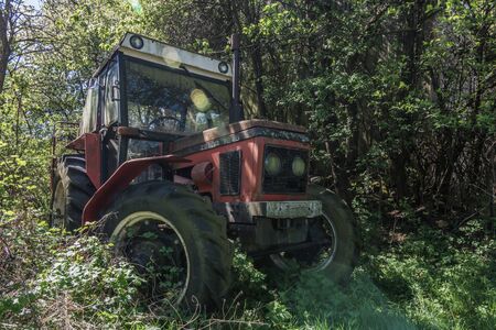 overgrown red old tractor in the forestの写真素材