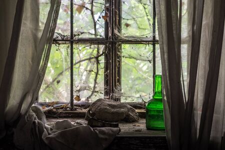 glowing green bottle on a window of an old houseの写真素材