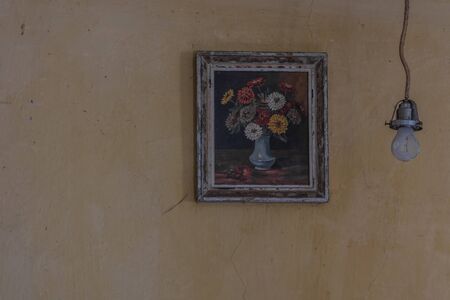 picture with flowers on the wall and a lamp in a room from a old houseの写真素材