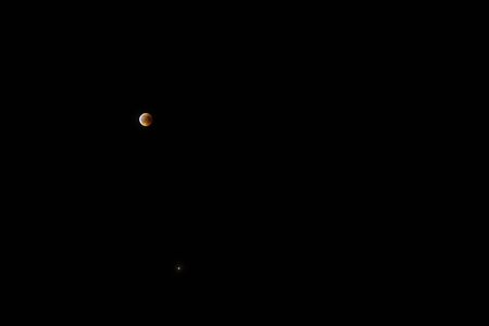 Partly covered moon during a lunar eclipse small in the dark sky at night
