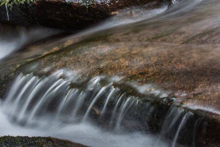 stage in a brook with flowing water detail viewの写真素材