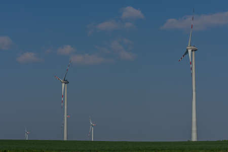 four wind turbines in the nature with sky and green field