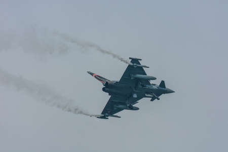 fighter plane with smoke and sky with rain at a air show in the summer