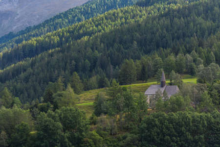 little church on a hill with a forest while hiking in the summerの写真素材