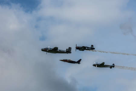 four different planes fly close to each other at a air show on cloudy sky