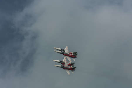 four red white planes fly close to each other on the sky with rain clouds