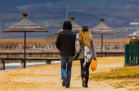 man and woman while walking at the lake in autumn with sunの写真素材