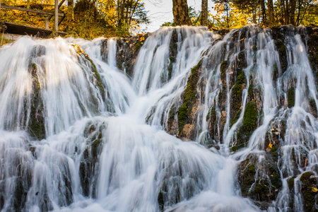 beautiful water ways at a large waterfall with colorful autumn forest in the nature