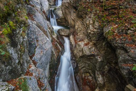 little waterfall with a stone between rocks in a gorge in the mountainsの写真素材
