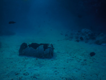 rusty old bin on sandy sea bottom with blue water while divingの写真素材
