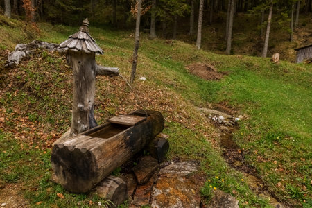 nice fountain made of wood near a house in the forest in the mountainsの写真素材