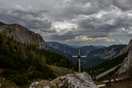 cross on a rock at the highest point on a mountain while hiking with wide viewの写真素材