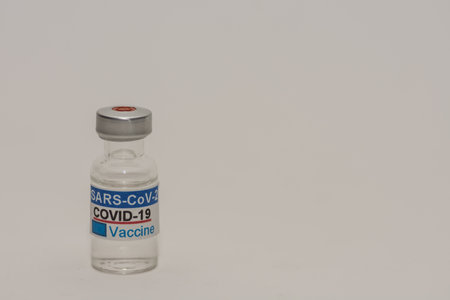 Covid vaccine against the virus in a bottle left gray backgroundの写真素材