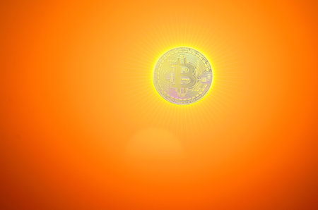 burning bitcoin instead a bright sun with little artifical sun rays on orangeの写真素材