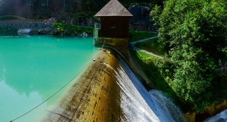dam wall with a waterfall at a water reservoir with a turquoise water panorama viewの写真素材