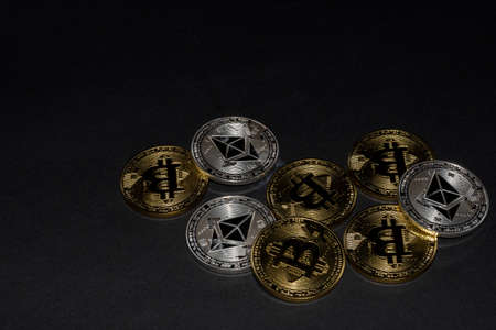 lying golden bitcoin and silver ether coins from cryptocurrency on black background