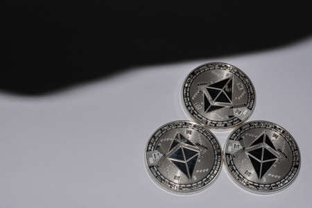 three silver ether coins from cryptocurrency on white background and black shadow
