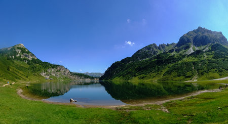 standing on the shore from a blue mountain lake with wonderful reflection from the landscape...