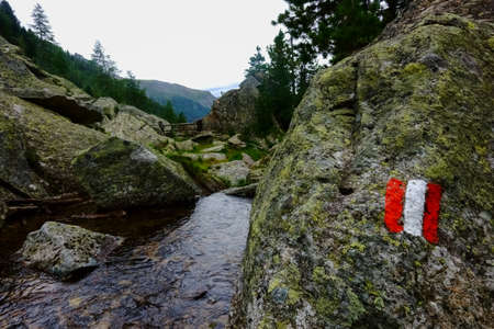 sign from austria on a rock next to a mountain stream while hikingの写真素材