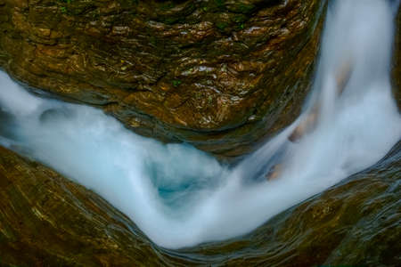 wonderful blue white twisted water between wet rocks in a gorge on vacationの写真素材