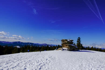 large rock on the top of a mountain with snow and blue sky in the winter