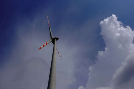 high wind turbine with white cloud and dark blue sky