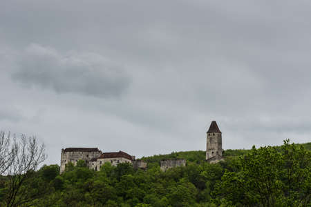 old castle in green hills with many trees and rain clouds in the mountainsのeditorial素材