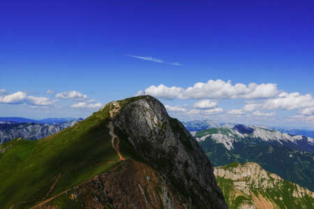 amazing steep mountain with a summit cross and wide view to other mountains with blue sky