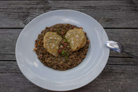 lentils with dumplings on a white plate with a spoon on a table on a mountainの写真素材