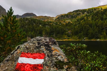 austrian waymark on a rock with view to the mountains and lakeの写真素材