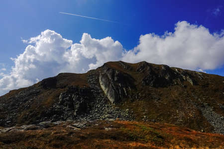 colorful mountain with blue sky and a airplane over the clouds