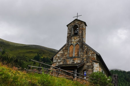 nice old little church with a wooden fence in the mountains of austriaの写真素材