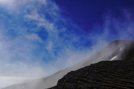 dark blue sky and strong current with white fog at a mountain while hikingの写真素材