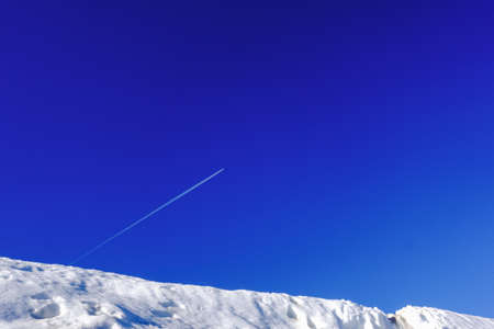 deep blue sky with a flying airplane and a white snow in the foreground