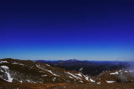 wide view to a mountain range with snow fields and deep blue sky while hikingの写真素材