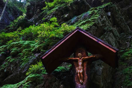 wooden wayside shrine near green rocks in a forest while hiking in austriaの写真素材