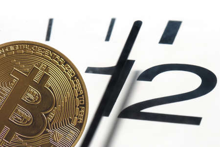 golden value bitcoin and a clock 5 minutes before twelve on white background