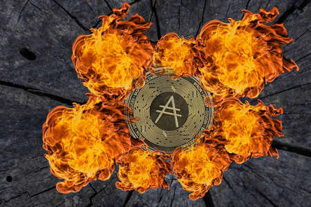 single golden ada coin from cardano currency on a tree trunk with fire aroundの写真素材