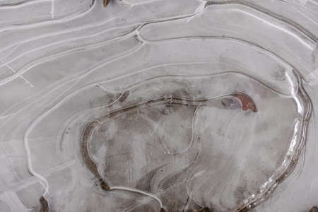 frozen puddle on a dirt road in the winter detail viewの写真素材