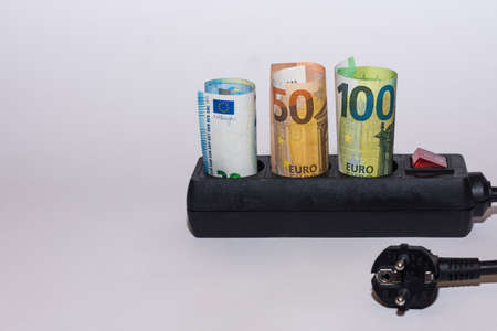Energy consumption and increase in electricity prices three Euro bills in a power strip with a plug right sideの写真素材