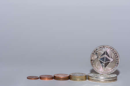 euro coins and valuebable ether coins from crypto currency stacked in a row with gray backgroundの写真素材