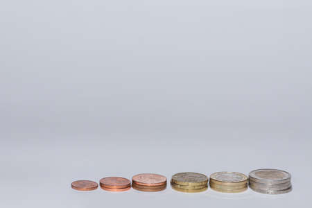 many euro coins stacked in a row increasing in value with gray background view above