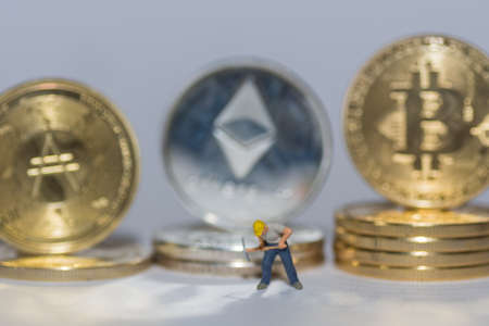 valueable crypto coins bitcoin ether and ada in a row with a single worker on gray background