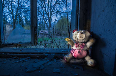 luminous plush bear standing on the windowsill from a abandoned houseの写真素材