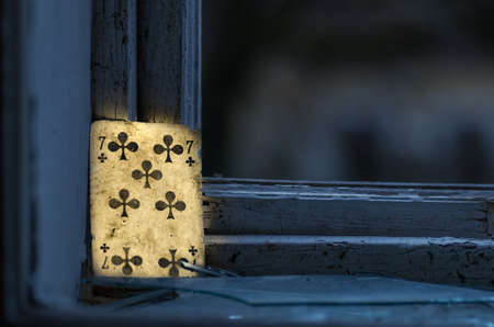 luminous playing card standing on the windowsill from a abandoned houseの写真素材