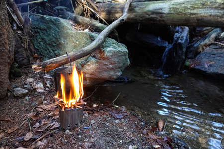 bushcrafting with a pot and boiling water over a fire by a creek