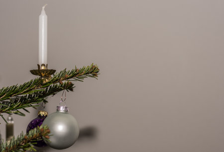 white candle and balls hanging on a christmas tree with gray backgroundの写真素材