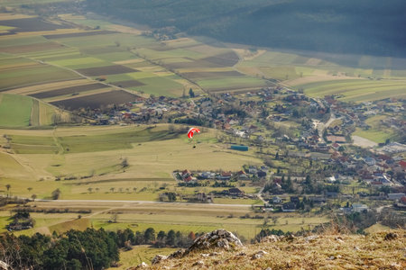 single colorful paraglider at a mountain in a green valley in the winter